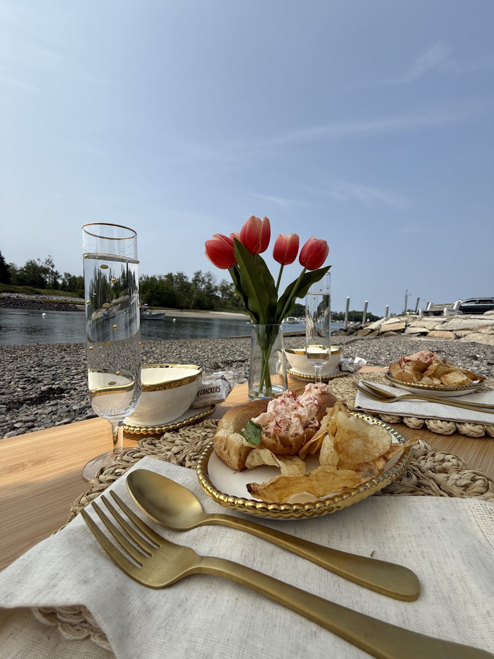 Outdoor table setting with tulips and elegant glassware by the water.