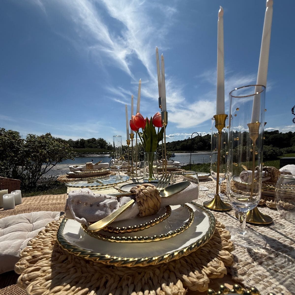 Luxury beach picnic setup in Maine with pillows, rugs, and styled table decor